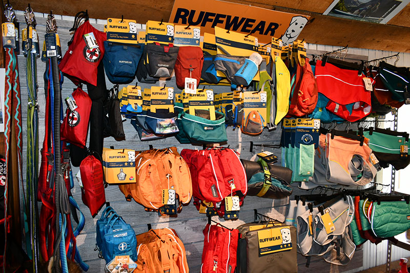 A wall of backpacks and bags hanging on the side.